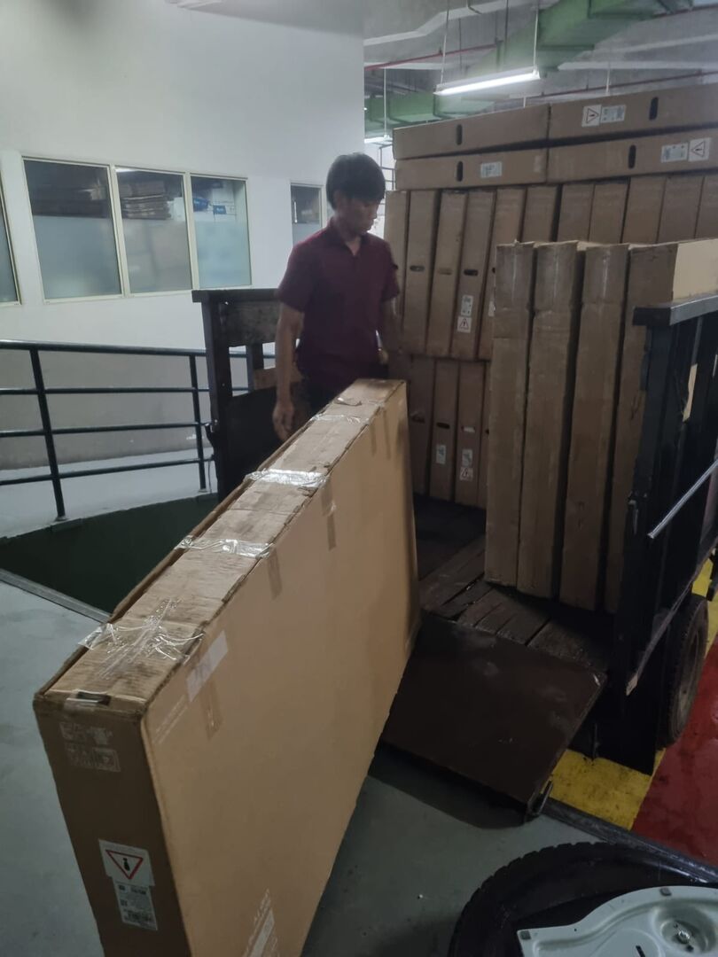 Unit TV layar besar dipindahkan dengan troli saat pengambilan borongan